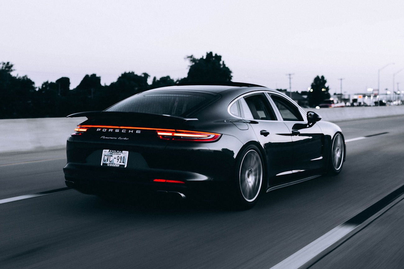 Чёрный Porsche Panamera 4S на трассе в движении в сумерках