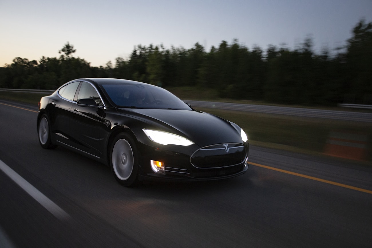 Чёрная Tesla Model S Plaid на шоссе в движении на закате